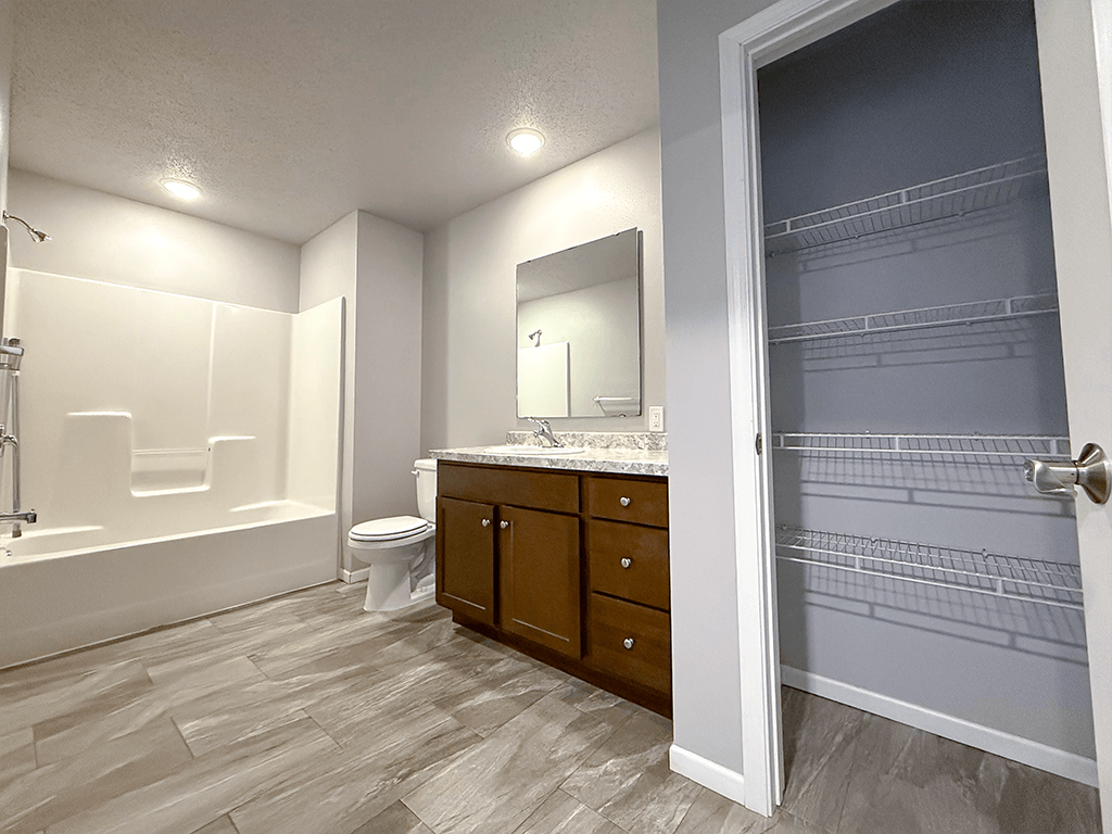 A bathroom with a walk in shower, toilet, sink and a large mirror.