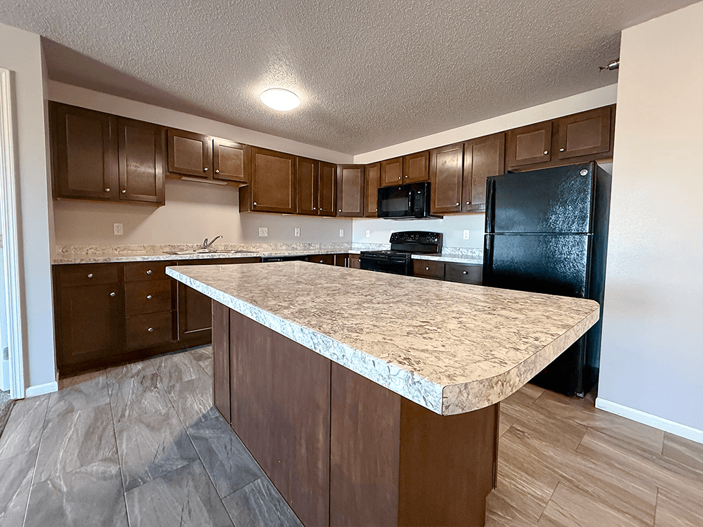 A kitchen with a granite countertop and wooden cabinets.