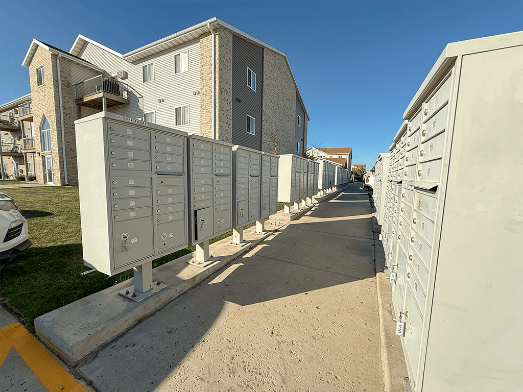 A row of mailboxes are lined up on a sidewalk.
