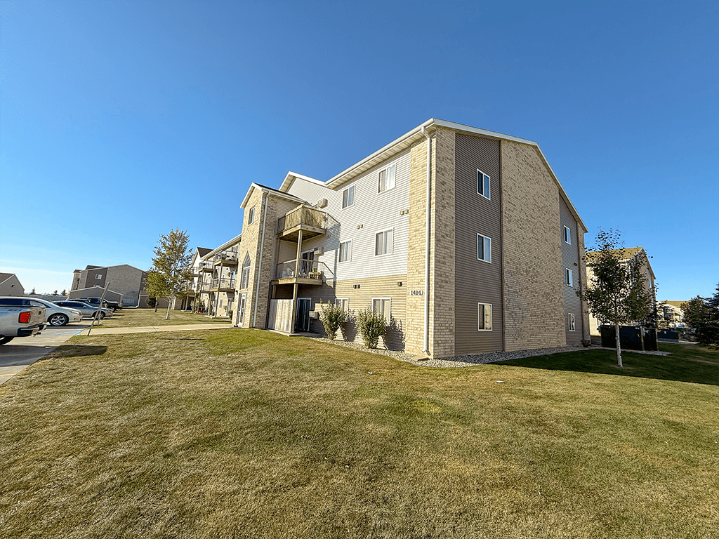 A large apartment building with a parking lot in front.