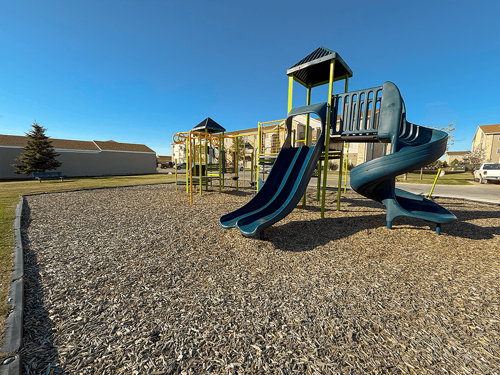 A playground with a blue slide and a yellow structure.