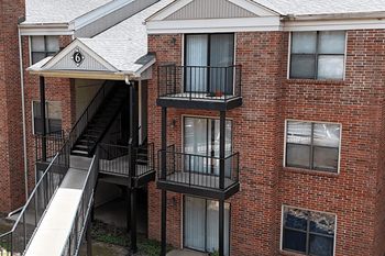A brick building with a balcony and a staircase leading to the second floor.