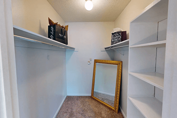 A mirror is on the floor in a walk-in closet with shelves.