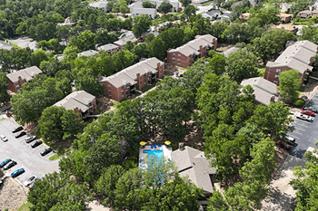 A bird's eye view of a residential area with houses, trees, and a swimming pool.