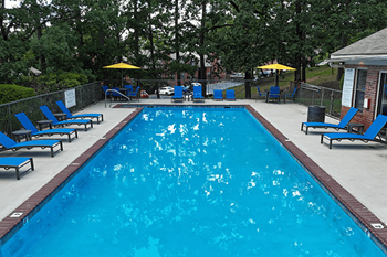 A large blue swimming pool surrounded by lounge chairs and umbrellas.