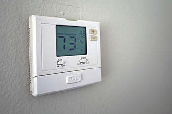 A white thermostat with a digital display showing 73 degrees.