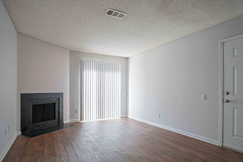 an empty living room with a fireplace and wood flooring