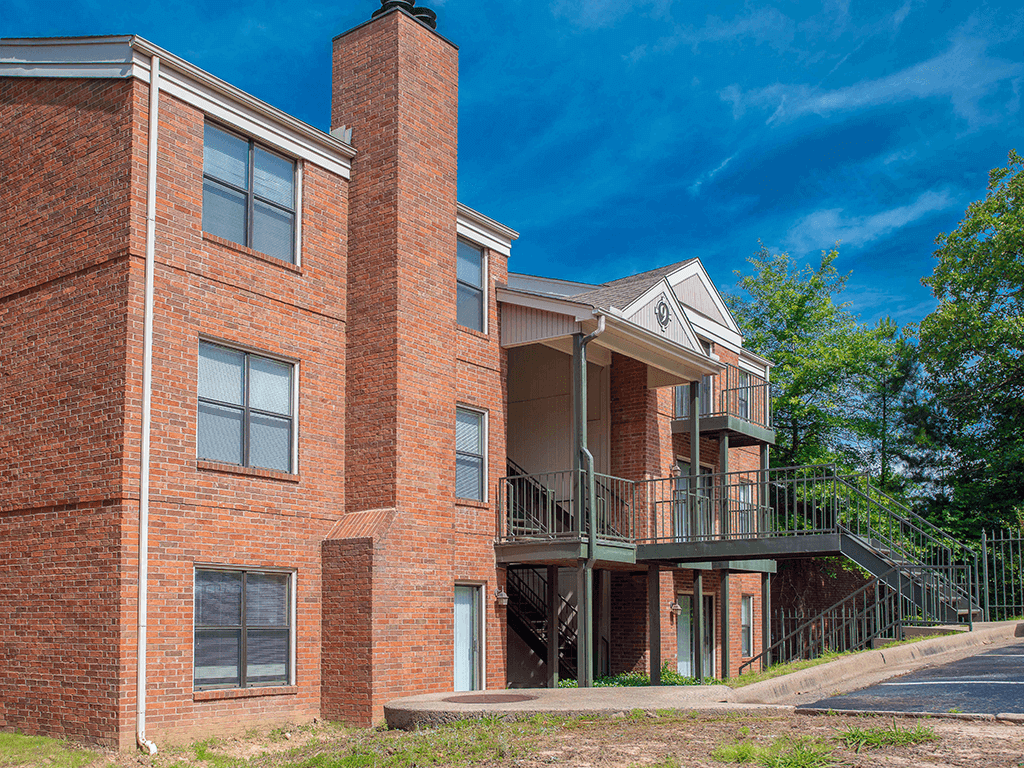 a brick apartment building with a balcony and a blue sky