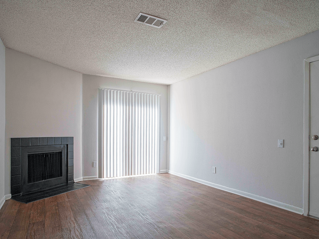 an empty living room with a fireplace and wood flooring