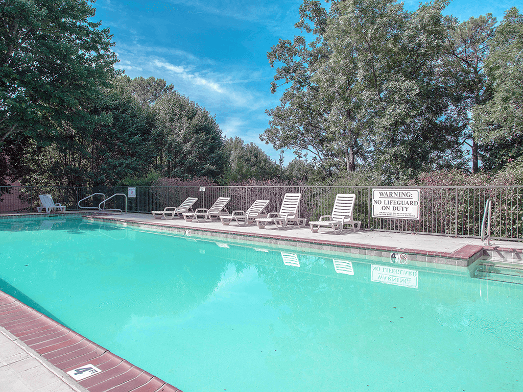 a swimming pool with chaise lounge chairs and trees