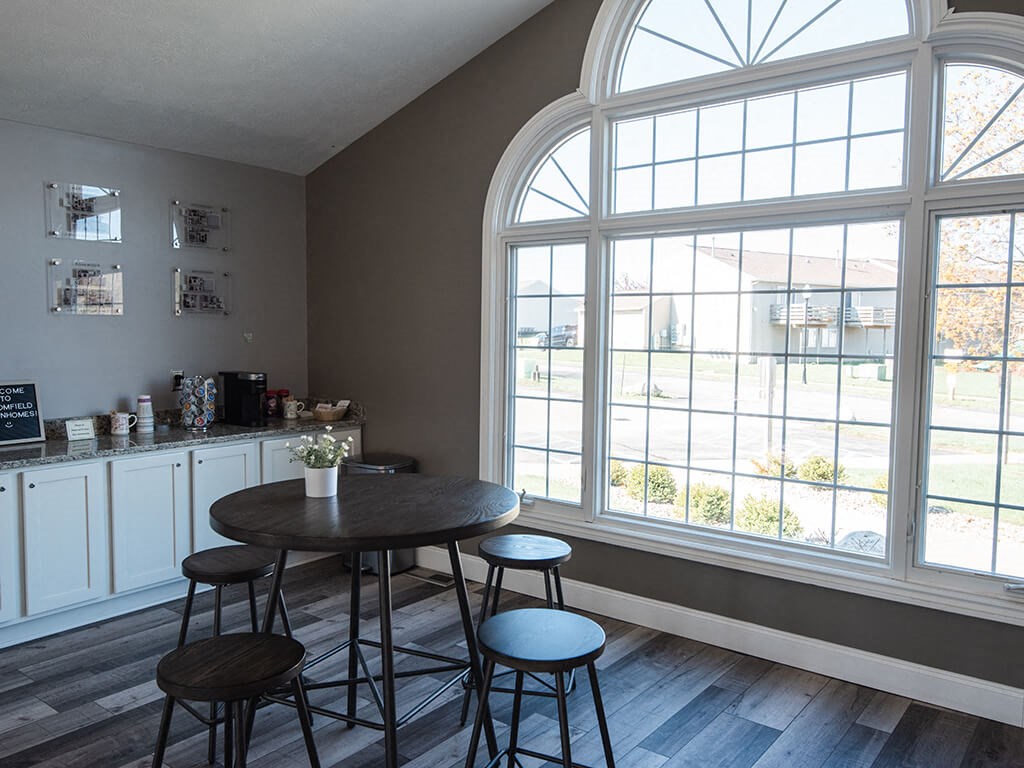 an empty room with tables and chairs and large windows