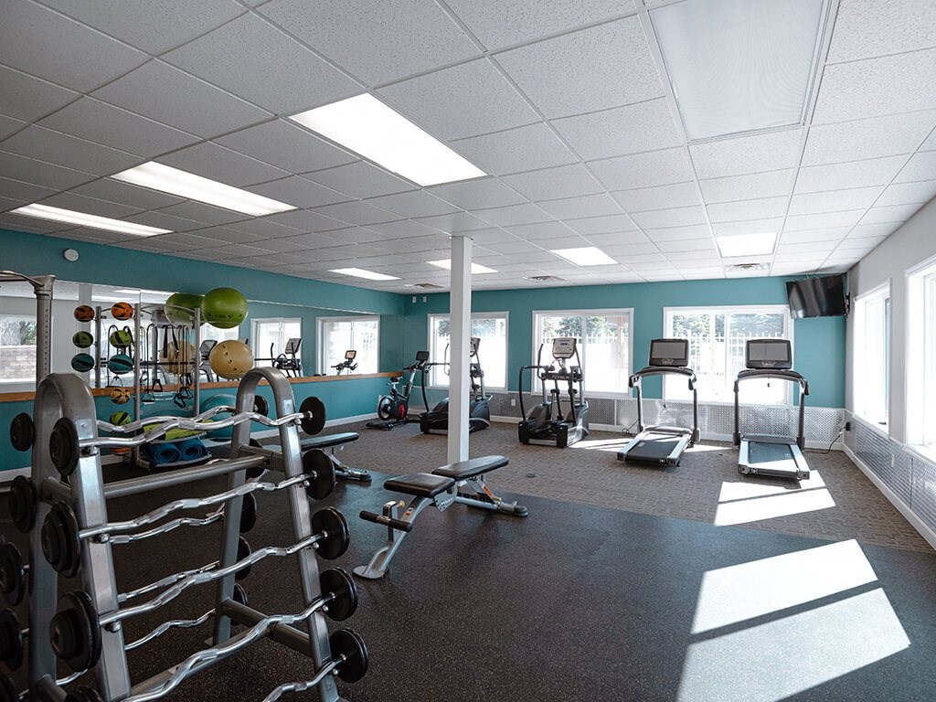 a gym with weights and other equipment in a room with windows