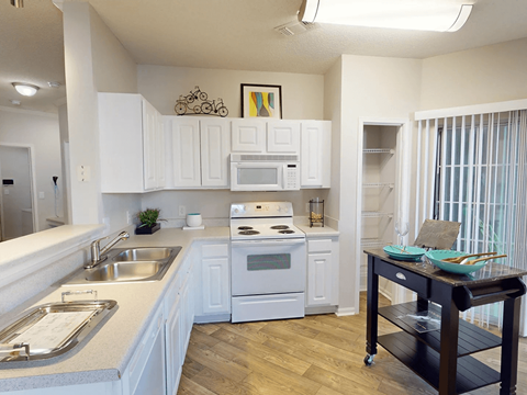 a kitchen with white cabinets and a sink and a stove