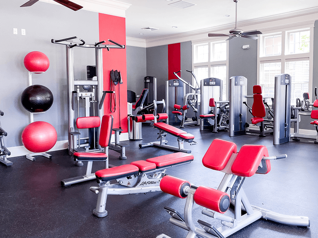 Apartment community gym with a variety of equipment including weights and benches.