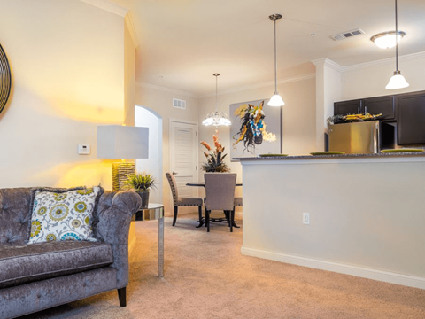 A living room with a grey couch and a bar area.