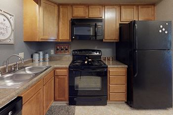 kitchen area with refrigerator, oven, and microwave at castle pointe apartments in east lansing