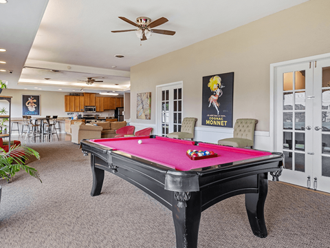 A pool table in a room with a ceiling fan.