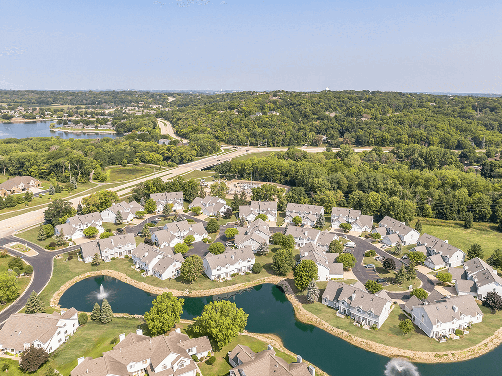 A bird's eye view of a residential area with houses surrounding a lake.