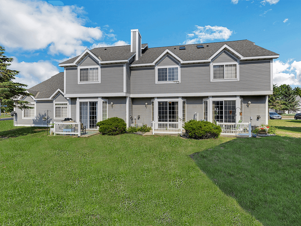 A large house with a grey roof and a white fence.