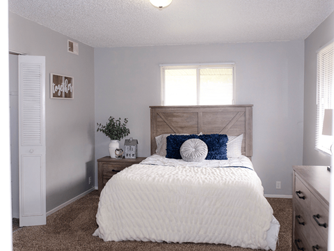 A white bed with a blue pillow and a white comforter.