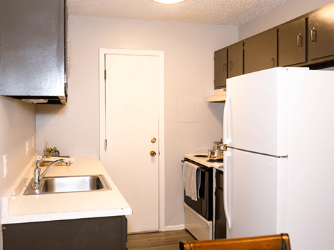 A kitchen with a sink, refrigerator, and cabinets.