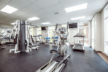 A gym with a variety of equipment including a treadmill, weights, and a stationary bike.