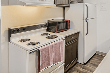 A white stove with a pink towel on it and a microwave on top of the stove.