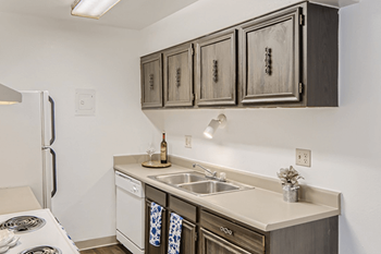 A kitchen with a stove, sink, and cabinets.
