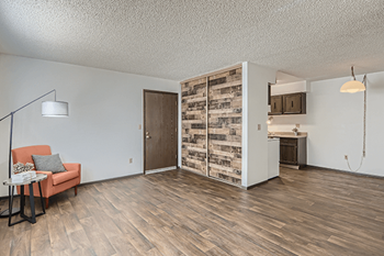 A room with a wooden floor and a chair with a pillow on it.