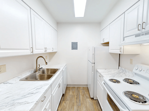 A kitchen with white cabinets and a white stove top oven.
