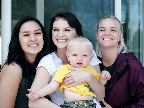 three people with a baby and smiling
