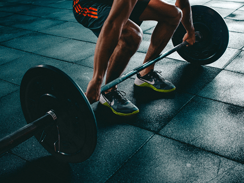 A man lifting a barbell in a gym.