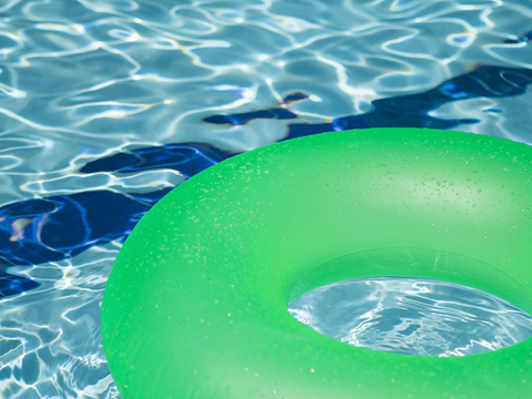 A green inflatable ring floating in a pool.