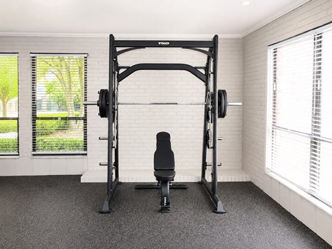 A black home gym setup with a squat rack and a bench.