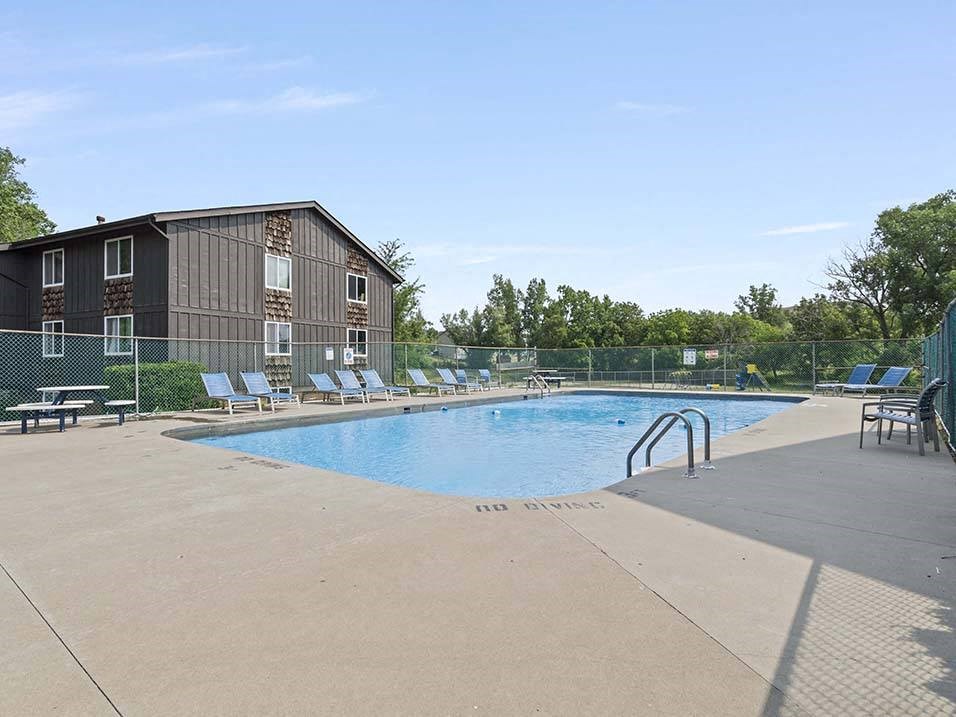 a swimming pool with chaise lounge chairs and a building in the background