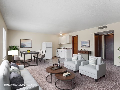 A living room with a grey couch, a coffee table, and a dining table with chairs.