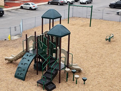 A playground with a green slide and a green roofed structure.