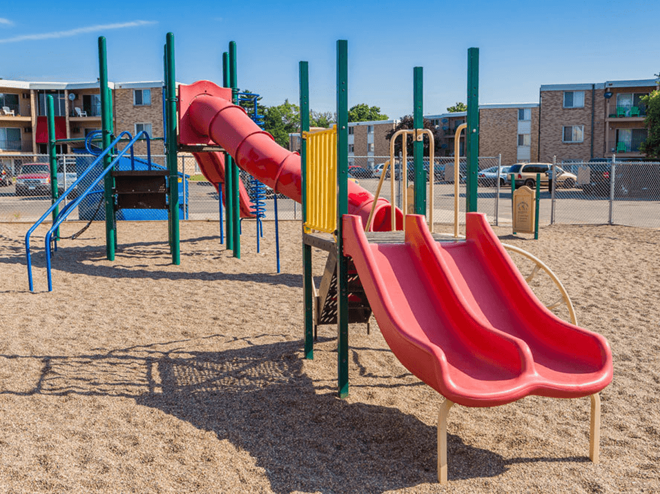 a playground with a red slide and a yellow slide
