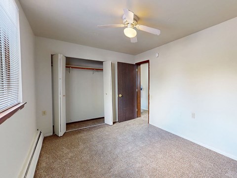 A room with a ceiling fan and carpeted floor.