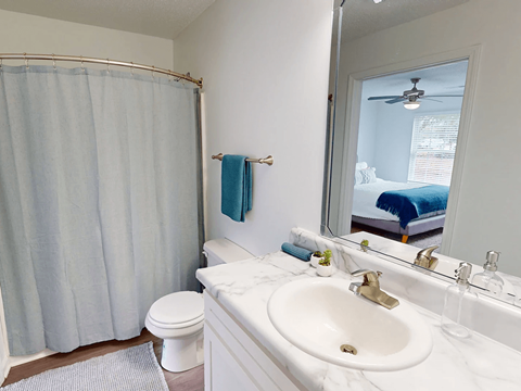 A bathroom with a white sink, toilet, and shower curtain.