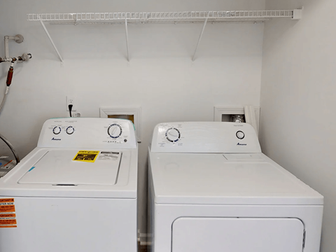 Two white front loading washing machines in a laundry room.