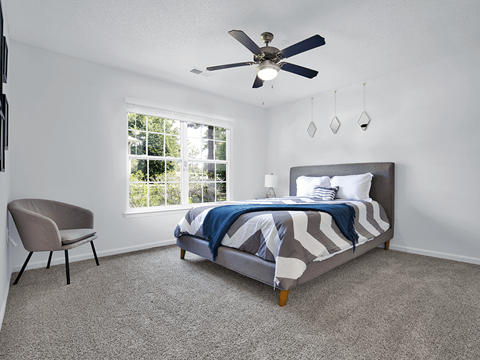 Apartment bedroom with a bed, window, and ceiling fan