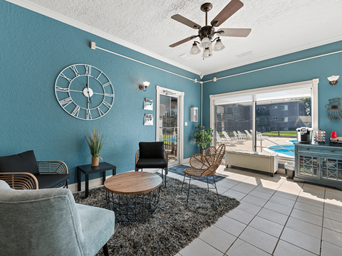 A living room with a ceiling fan and a large clock on the wall.
