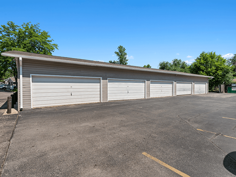 A parking lot with a building and four closed garage doors.