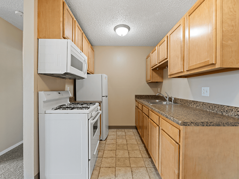 A kitchen with white appliances and wooden cabinets.