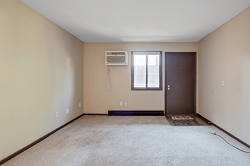 an empty room with a bathroom and a window and a air conditioner