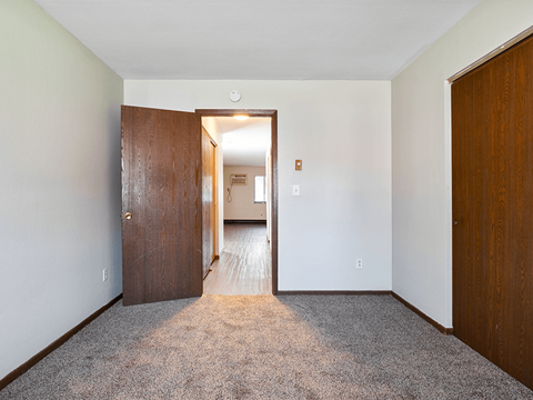 a bedroom with a door to a hallway and a carpeted floor