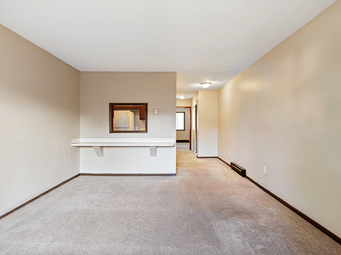 a spacious living room with white walls and carpeting and a white walled room