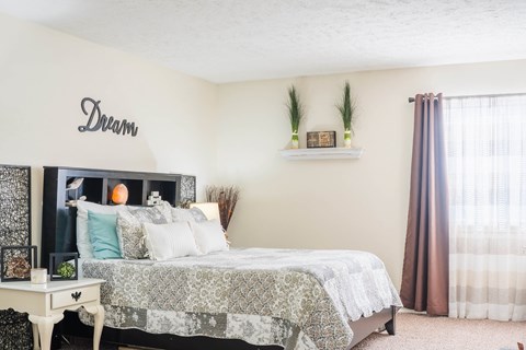 A bedroom with a bed, a nightstand, and a wall decoration that says