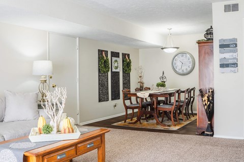 A living room with a couch, a coffee table, and a dining table set up.